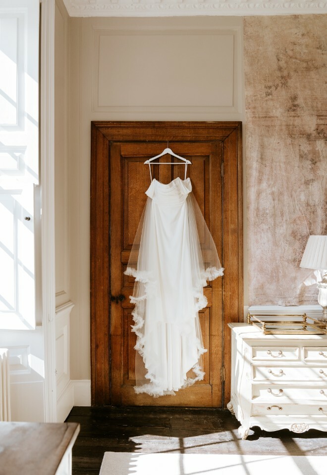 Brides wedding dress hanging from the door
