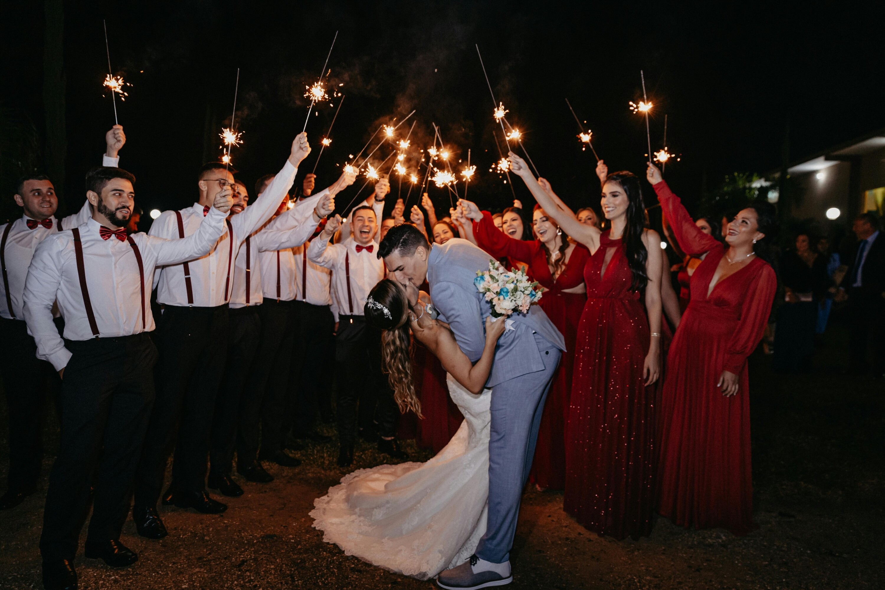 Wedding party standing around the bride and groom with sparklers
