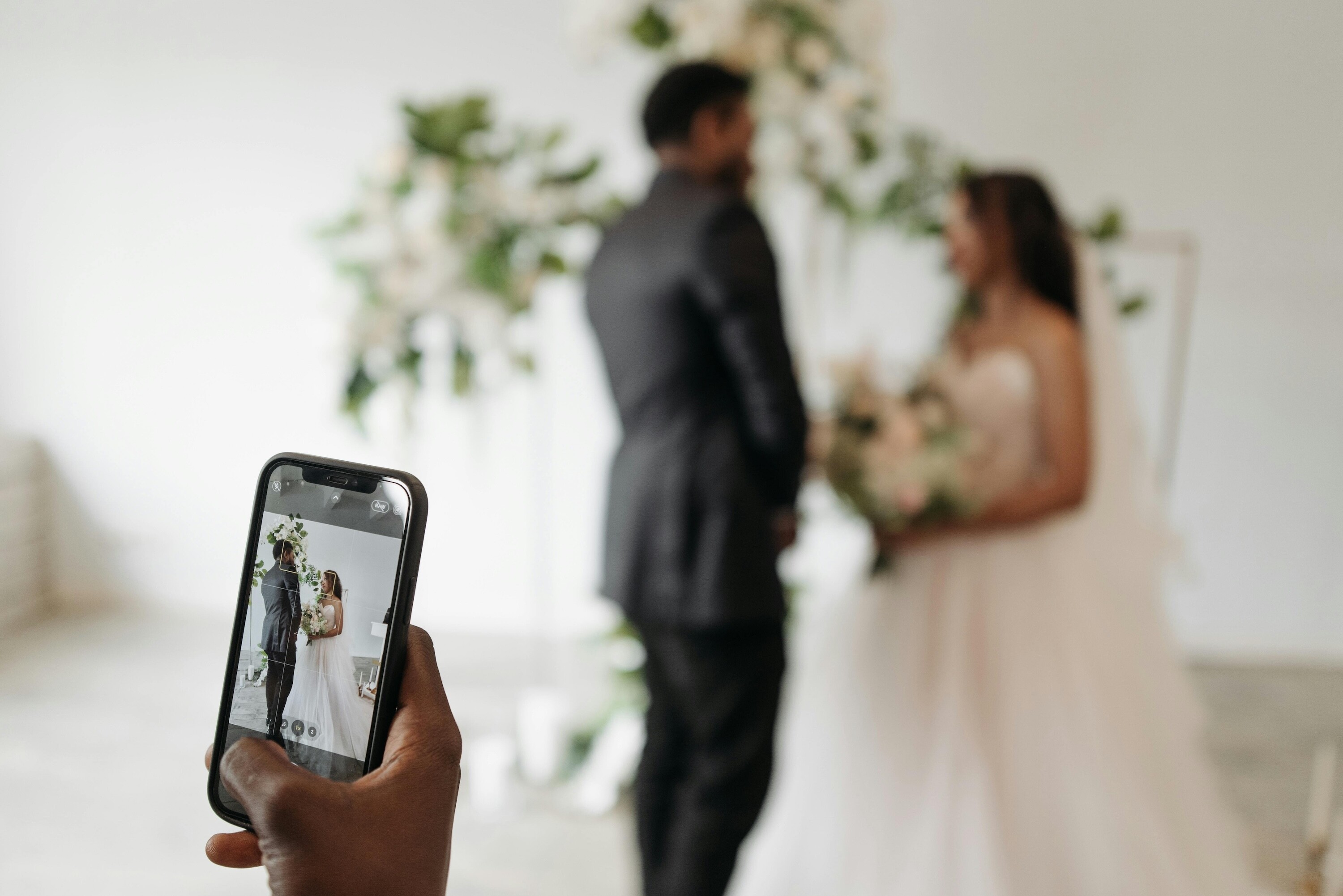 Guest capturing image of wedding couple on phone