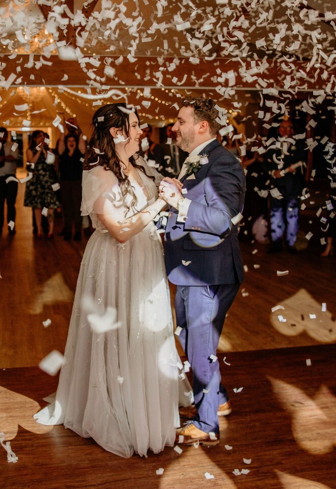 First dance under falling confetti with guests gathered around.