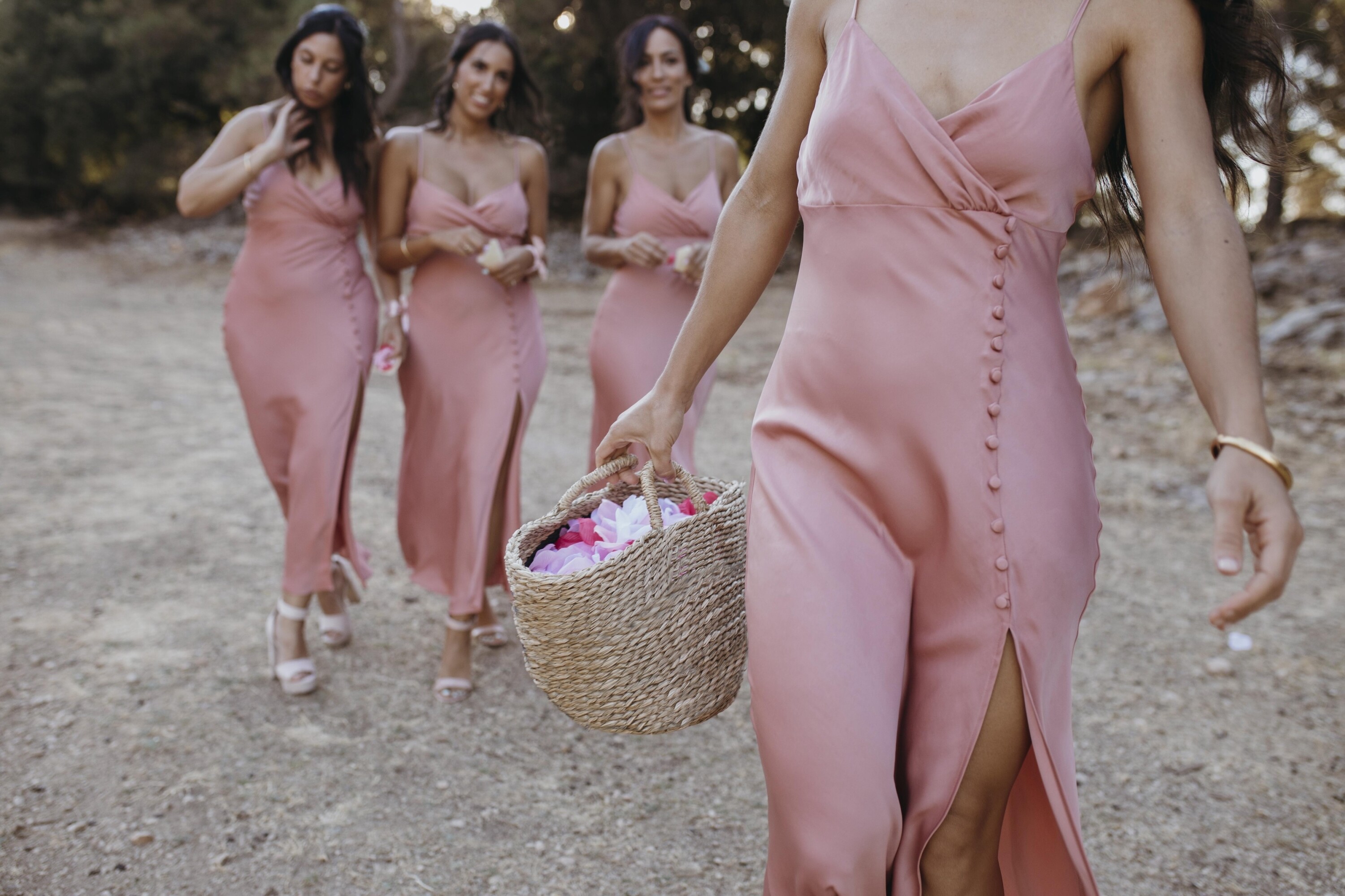 Bridesmaids dressed in pink spaghetti strap dress holding a basket of flower petals