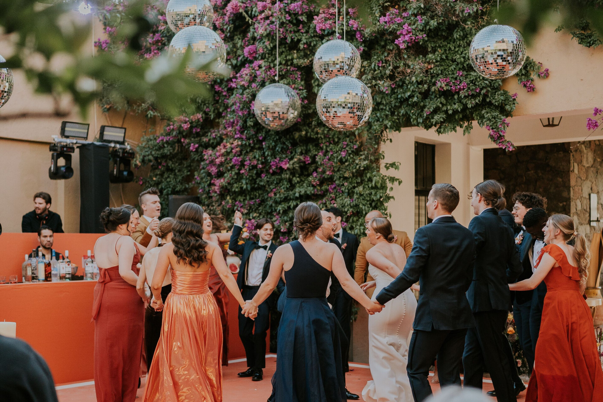 Wedding guests celebrating on the dance floor beneath disco balls and floral installations during the reception.