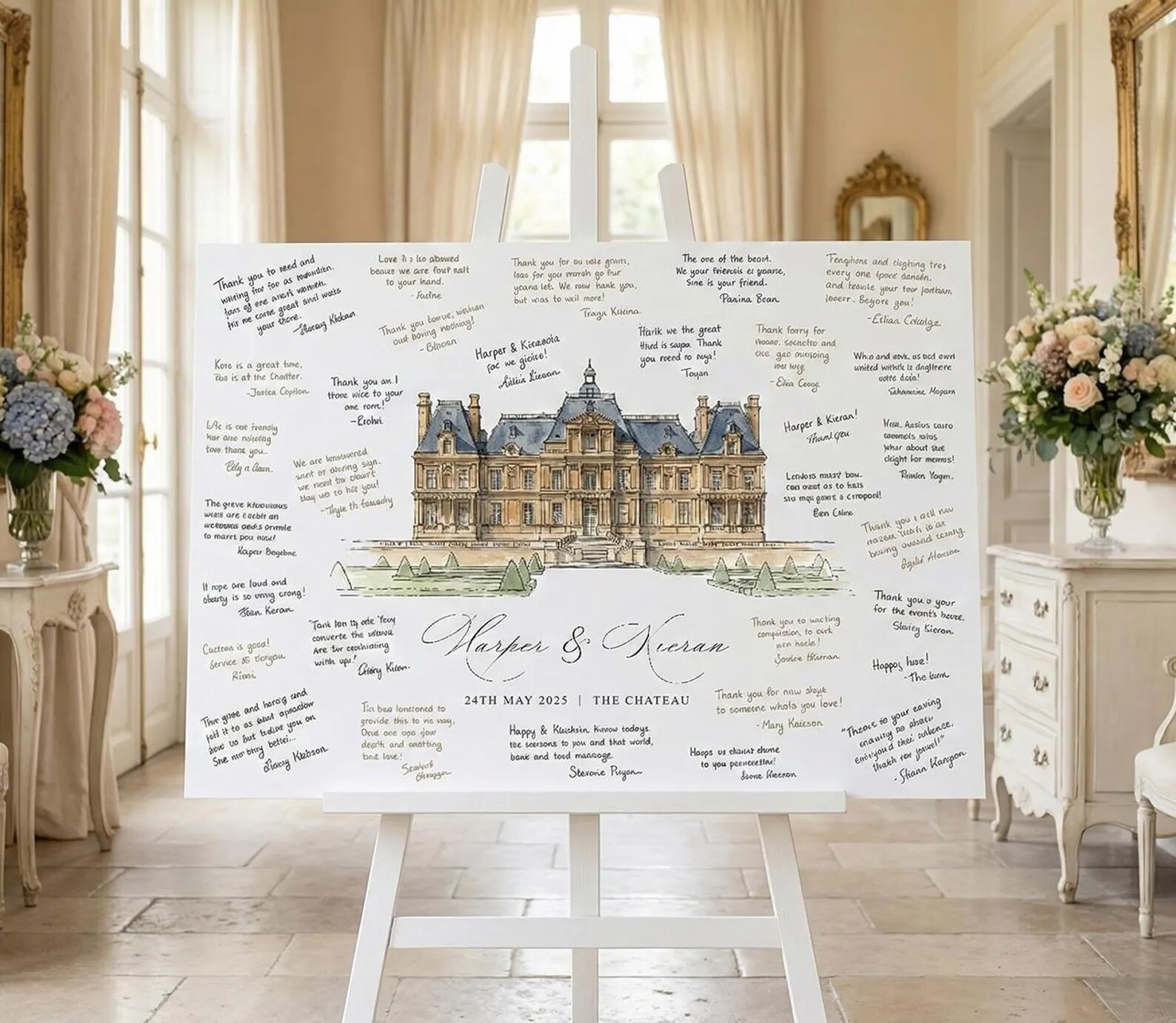 Wedding guest book alternative featuring a large illustrated venue print on an easel, with handwritten messages from guests surrounding the artwork in a bright, elegant reception space.