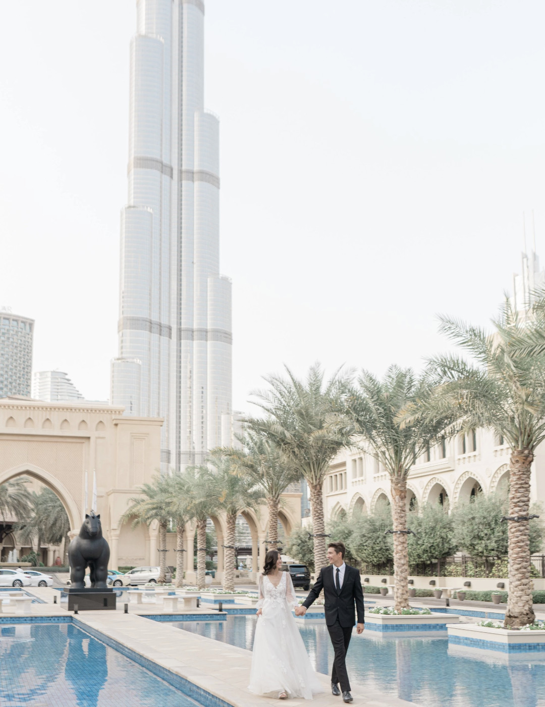 Bride and Groom walking down aisle with pools on either side and the Burj Khalifa in the background