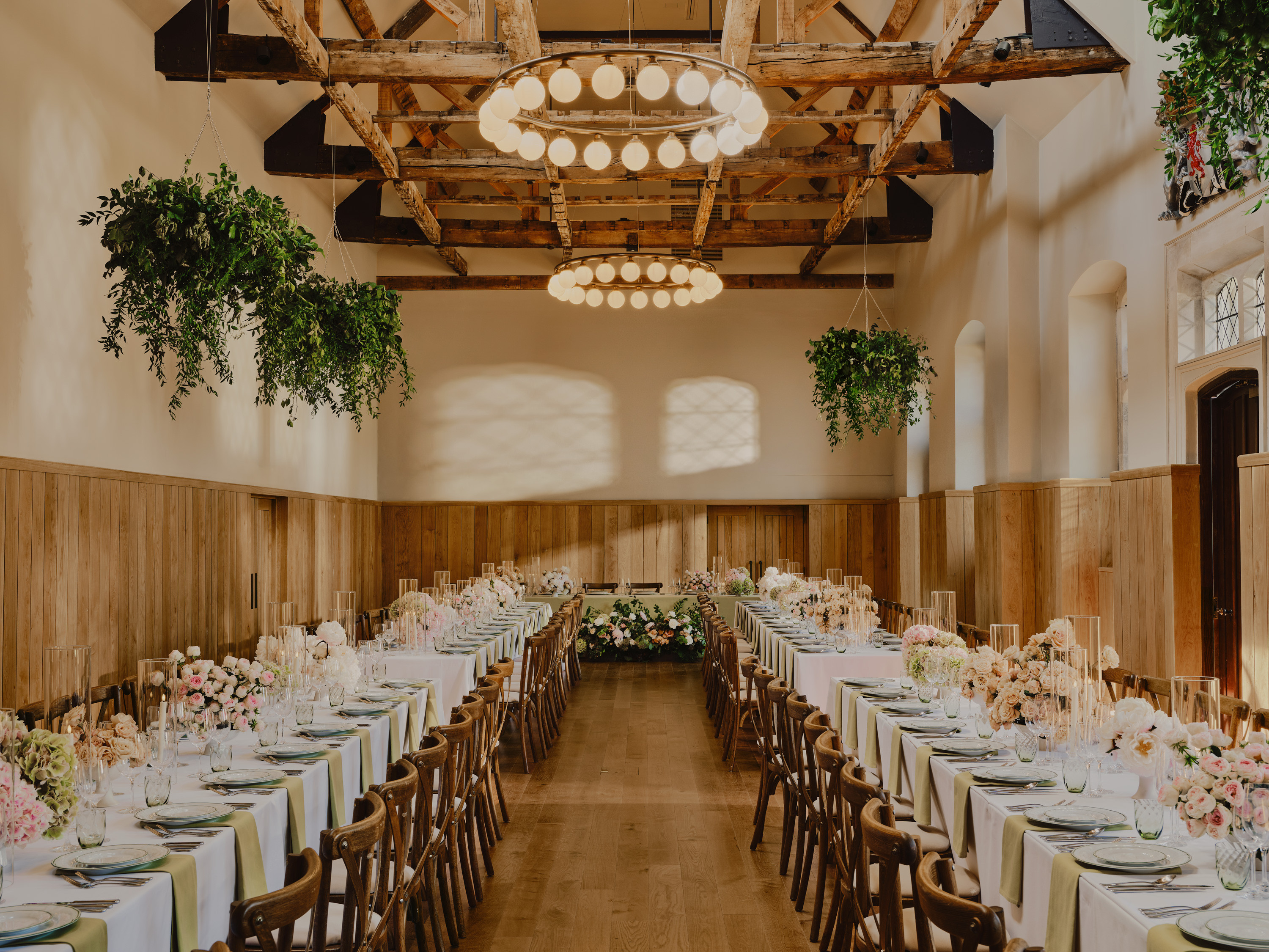 Wedding breakfast setup in The Coachhouse at Duke’s Yard with hanging greenery and banquet tables
