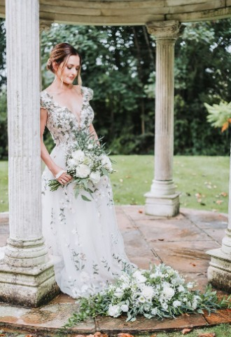 Bride leaning against a column from the island temple at Ardington House, gazing down.