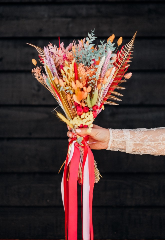 Brides bouquet of colourful dried flowers tied in pink ribbons