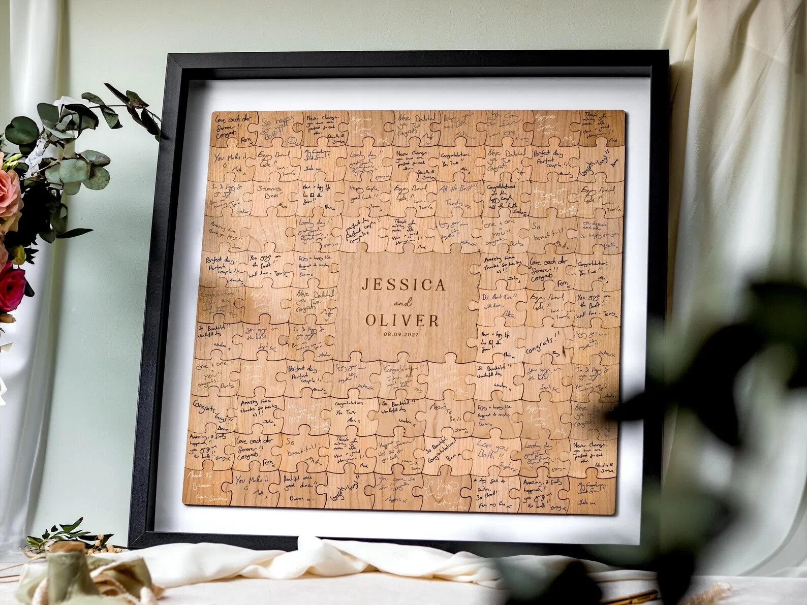 Framed wooden puzzle guest book with individual pieces signed by guests, featuring a central personalised section with the couple’s names and wedding date, styled as a finished keepsake.