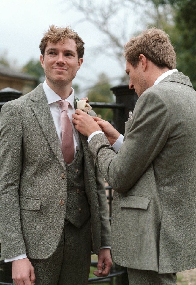 Groomsman helps groom with buttonhole
