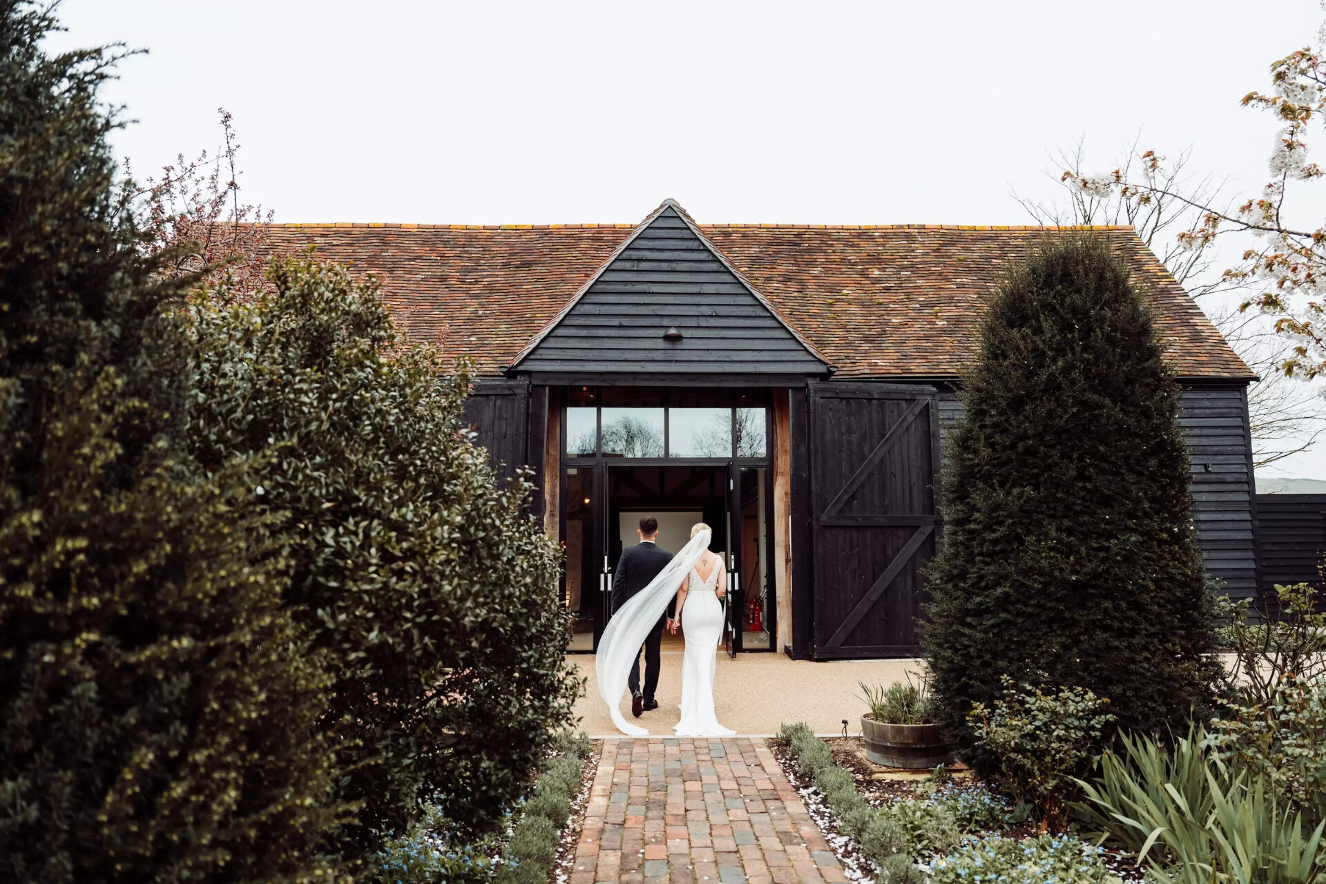 Couple walking into the Century Barn at Alfriston Gardens wedding venue in East Sussex.