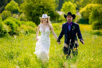 Bride and groom holding hands walking through a field