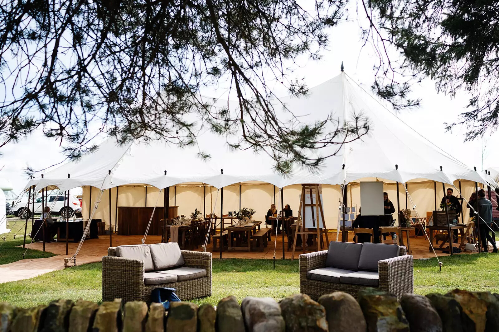 Open-sided wedding marquee with outdoor lounge seating at Eavestone Lake.