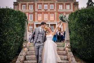 Bride and groom cheering in front of Ardington House