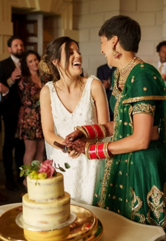 Ana and Satveer cutting their wedding cake together.