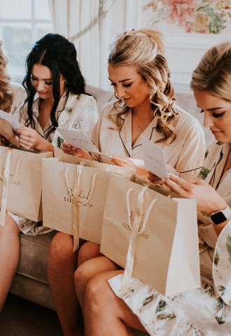 Bridesmaids receiving gifts on sofa at Hedsor House wedding venue Buckinghamshire