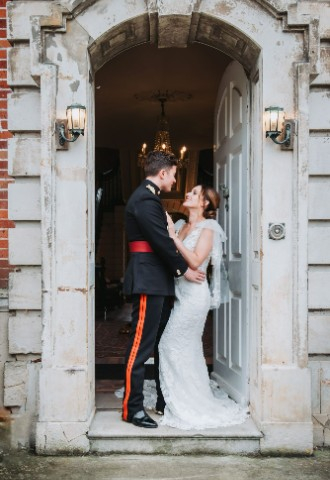 Bride and groom stood in the doorframe at Ardington House looking at each other.