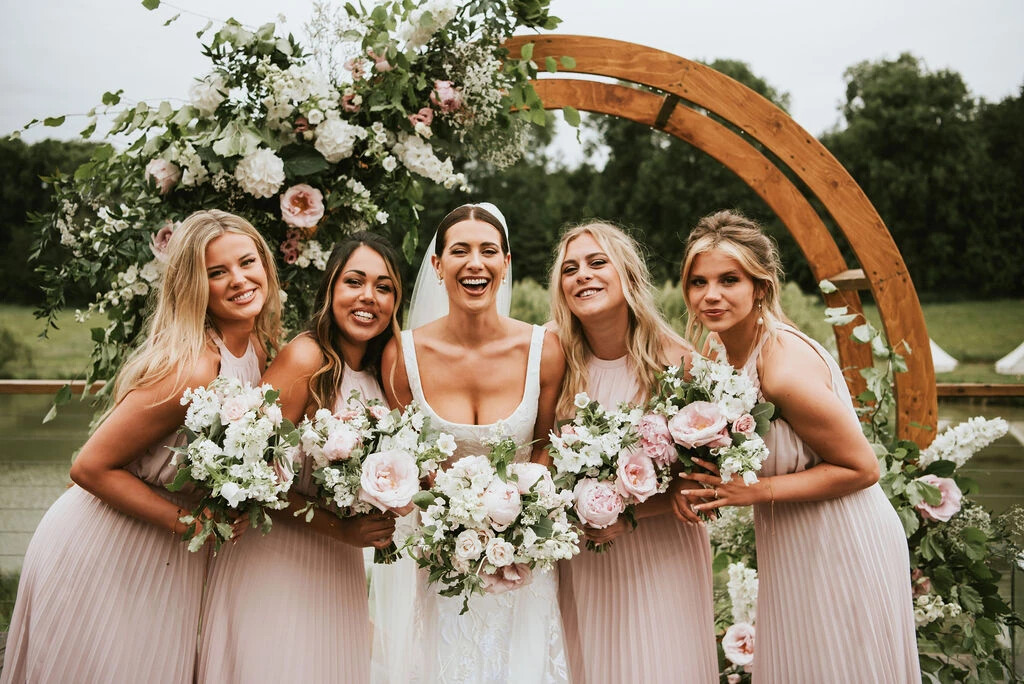 Bride and bridesmaids smiling while holding wedding bouquets