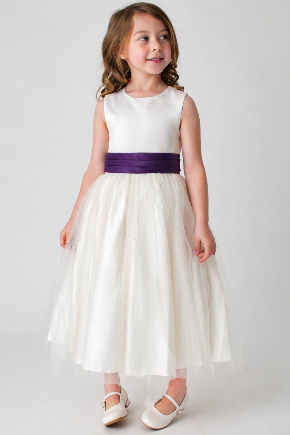 young girl in a ivory flower girl dress with purple sash with bow tie at the back