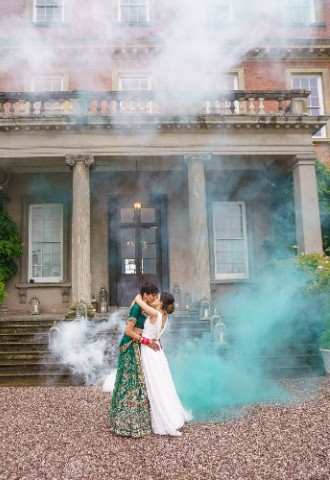 Ana and Satveer kissing in front of Davenport House holding colourful smoke bombs