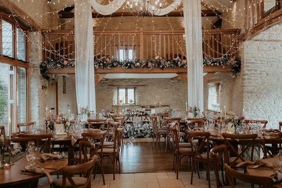 Wedding breakfast set up with draping, florals and light canopy at Kingscote Barn