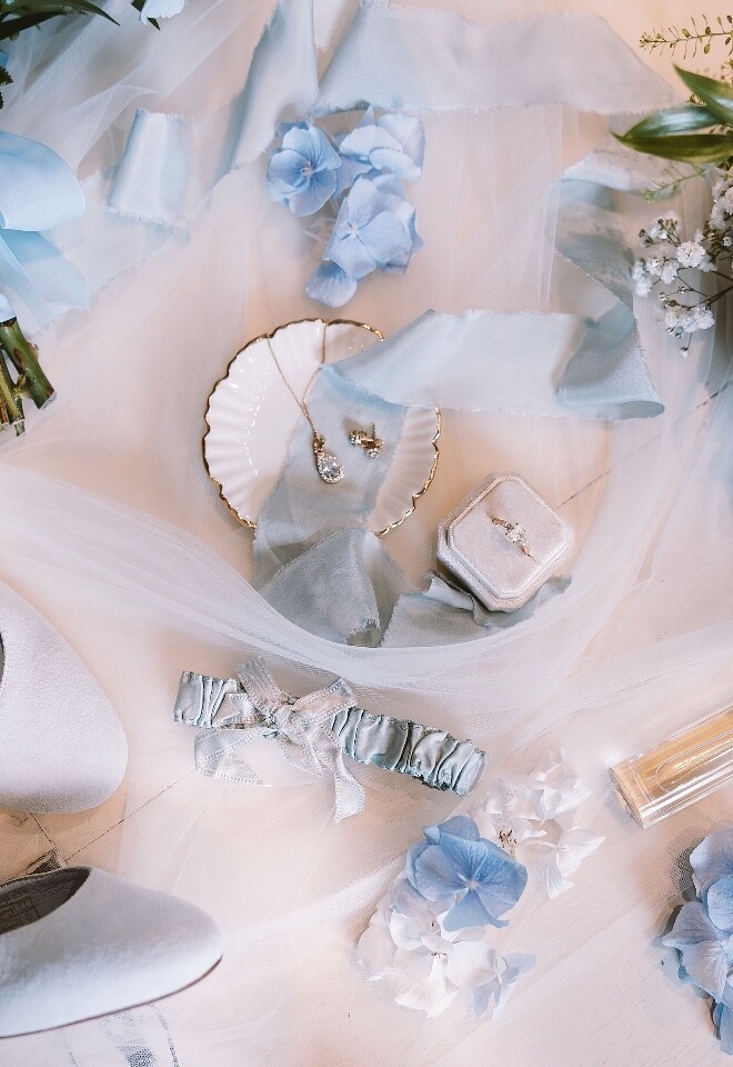 wedding details photo showing engagement ring, flowers, shoes, garter, jewellery and perfume in pale blue