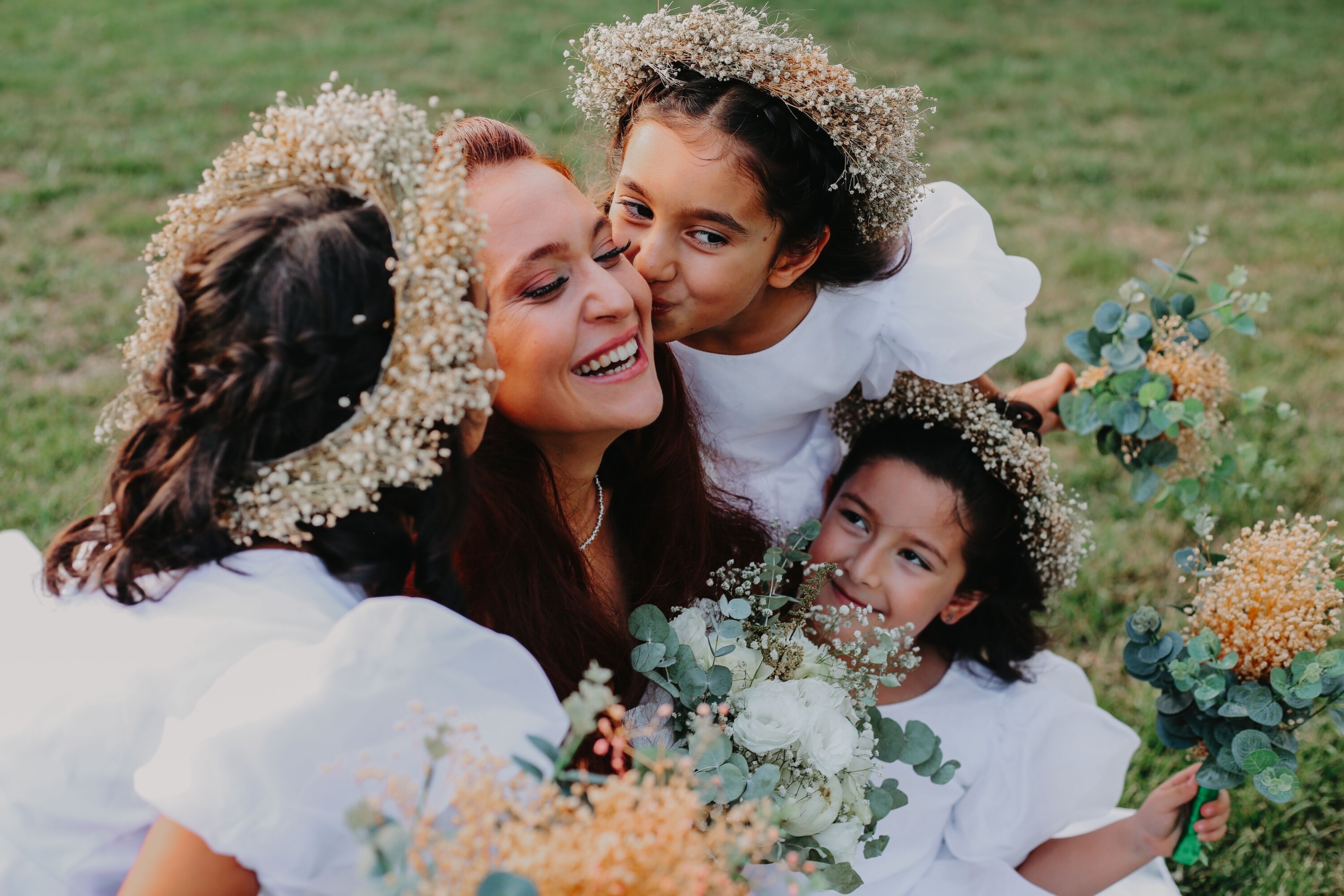 Flower girls kiss the brides cheek in a wedding photo