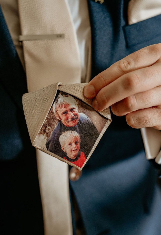 Groom revealing his tie, with a personalised photo patch inside of a sentimental family image.