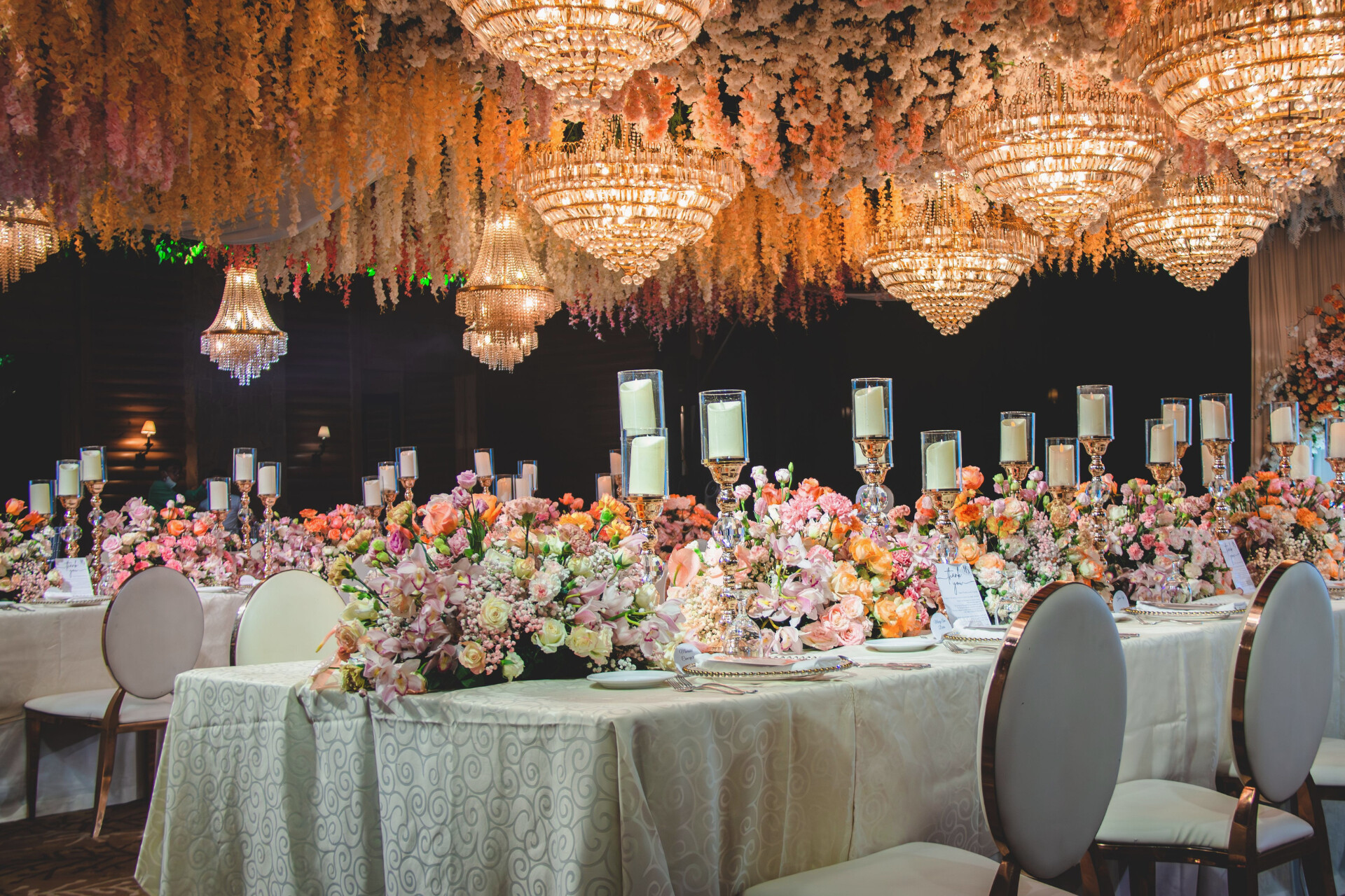Luxury wedding reception with crystal chandeliers, suspended floral installations and elegant tablescapes.