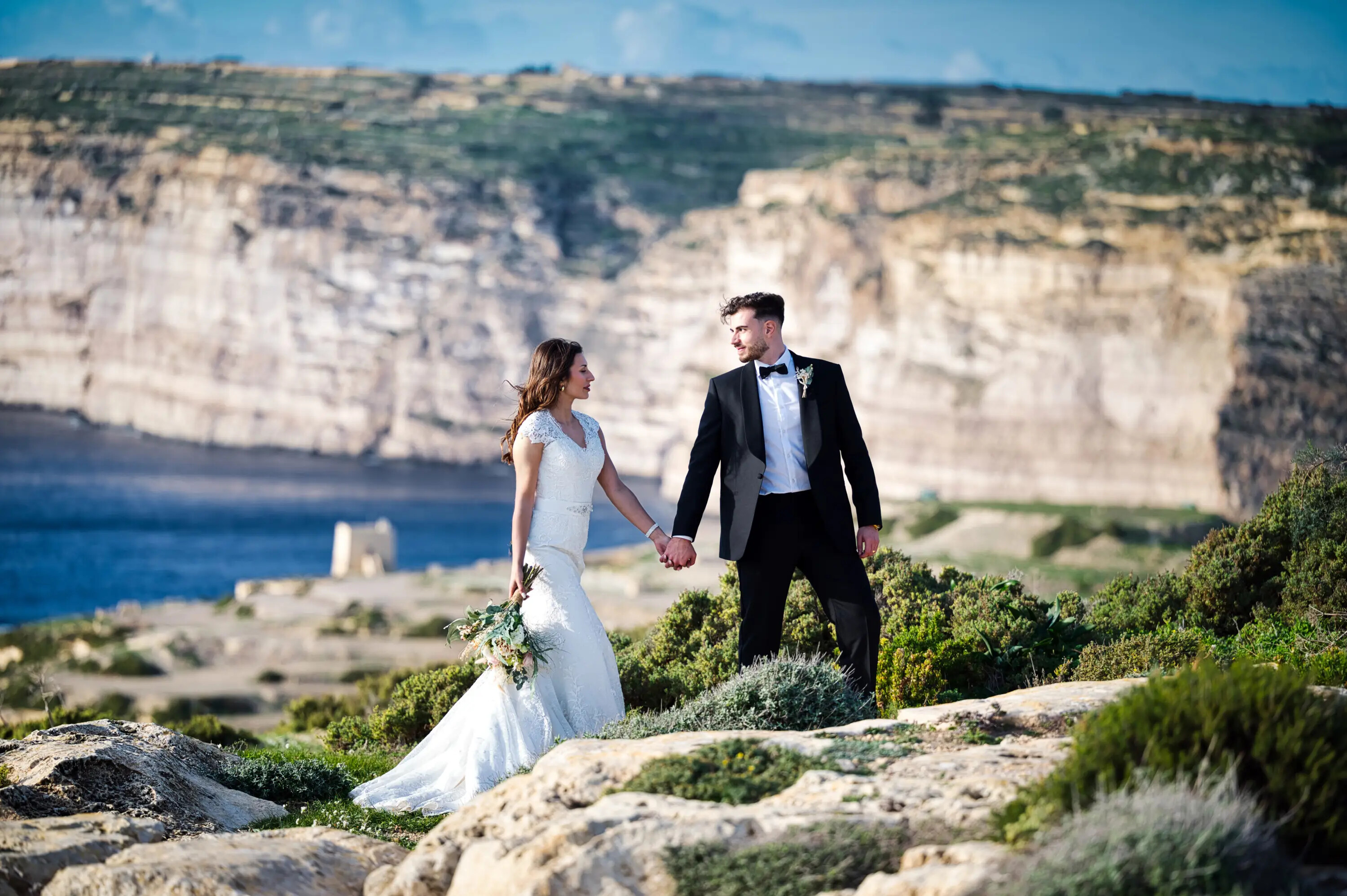 Bride and groom walking on cliffs in Malta