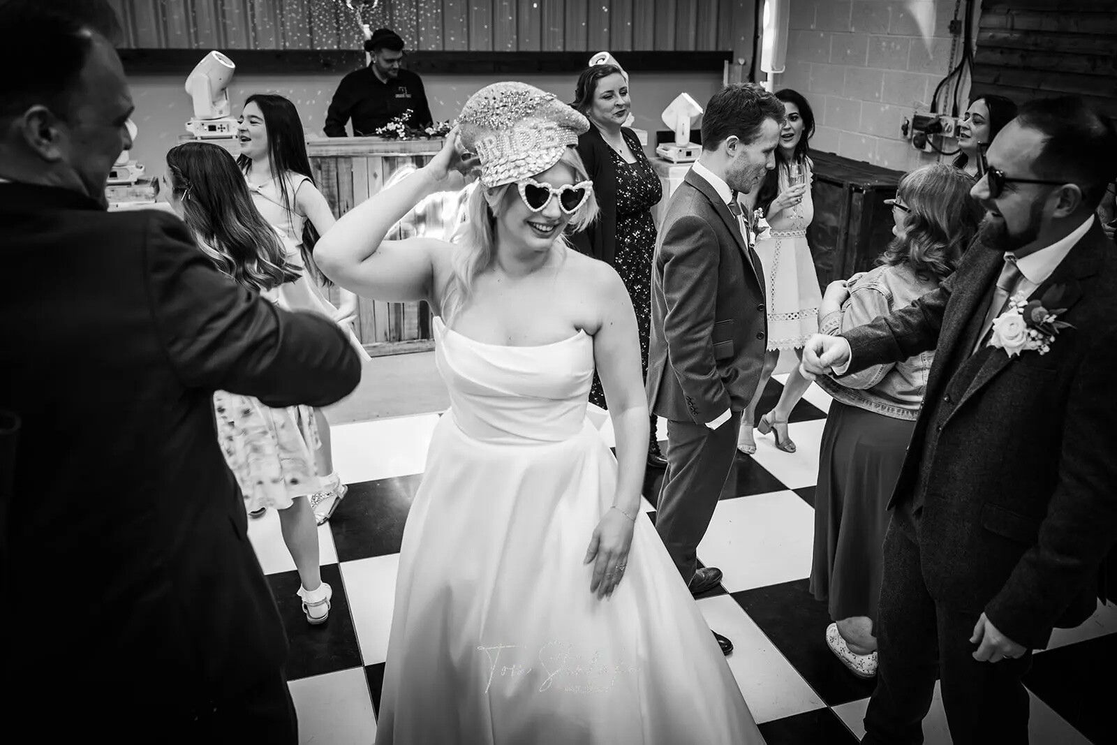 Bride dancing with guests on a chequered dance floor during a wedding reception with music by Together Events.