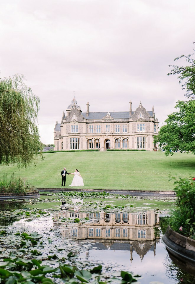 Bride and groom stood by the lake at Clevedon Hall