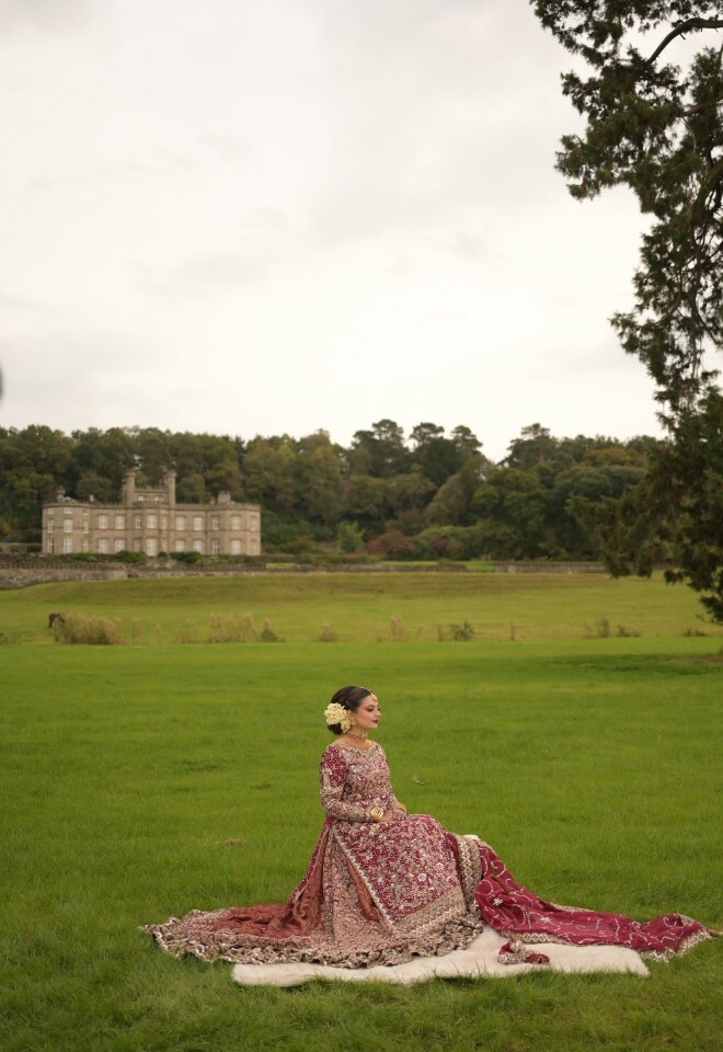 Bride sitting lavishly on the open grounds with the castle as the backdrop