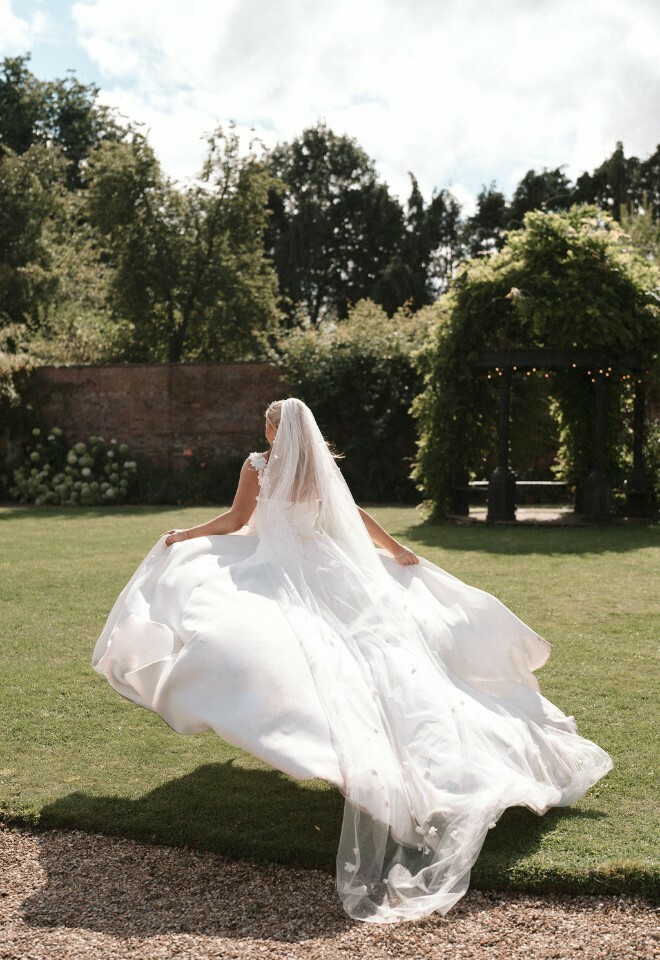 Bride runs through wedding venue grounds with dress flowing