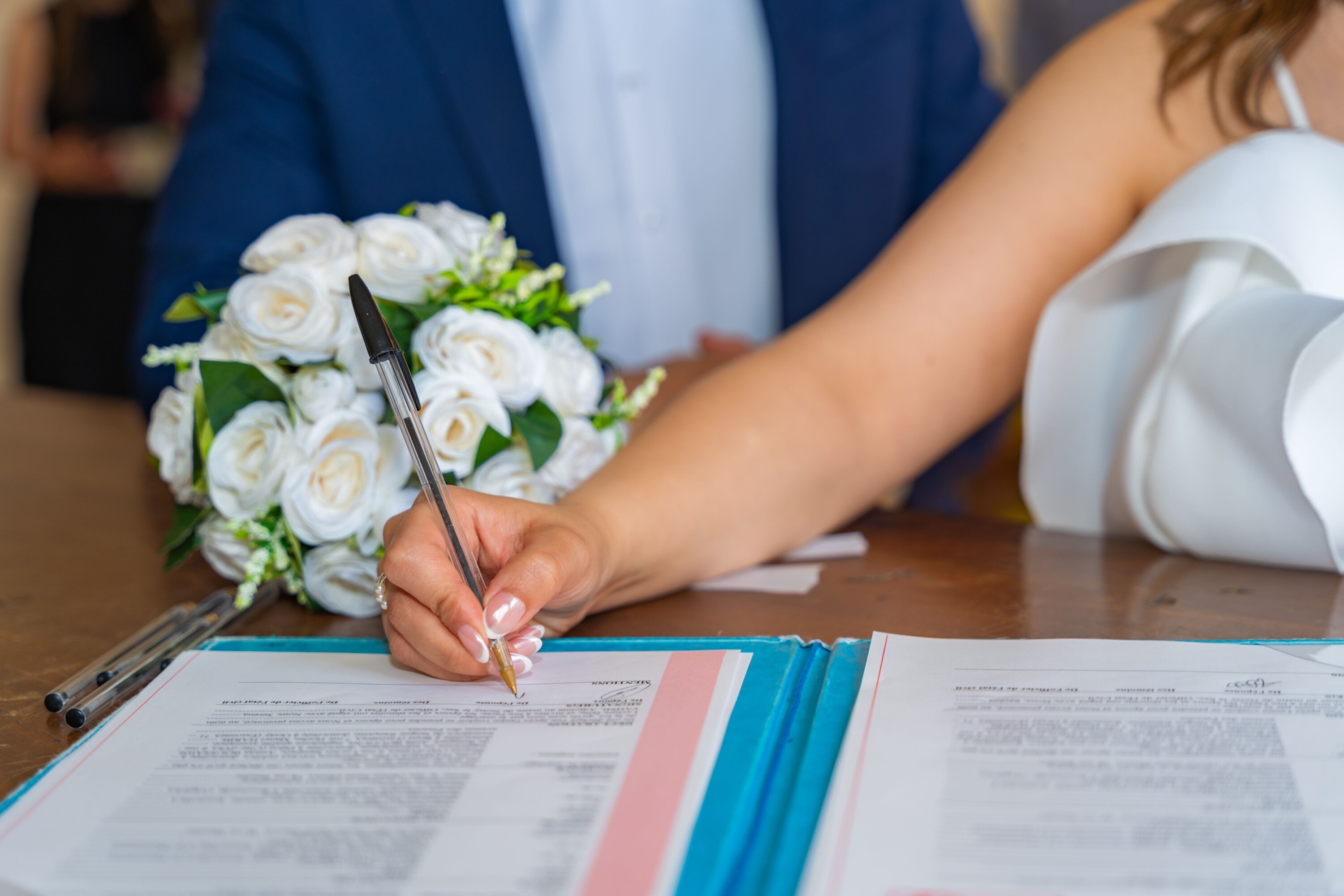 Close up of a brides hand as she signs legal document during wedding ceremony