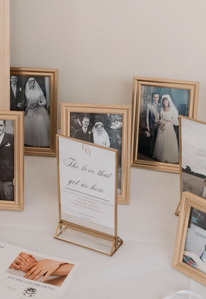Sign on table that reads "the love that got us here" surrounded by family wedding photos of parents and grandparents
