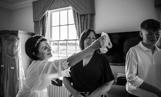 bride holding garter and bridesmaids getting ready
