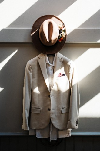 Ecru colour suit and hat hanging up on wedding morning