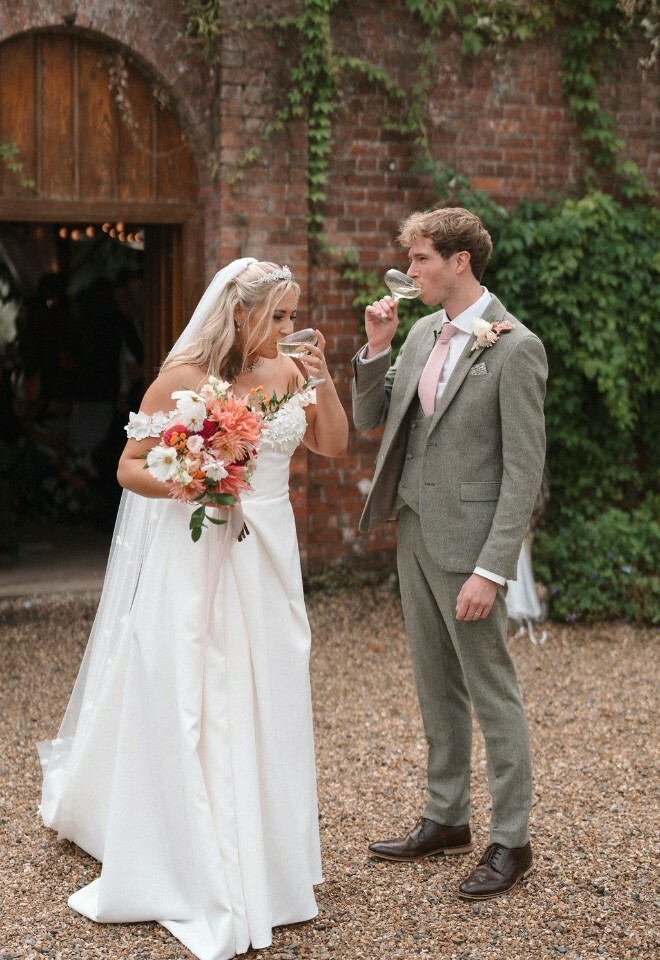 Bride and groom enjoy first drink as married couple from coupe glasses