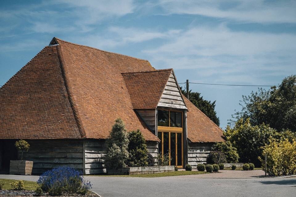 Exterior of Skylark Country Venue in Northamptonshire, featuring a timber barn with tiled roof, landscaped gardens and countryside surroundings.