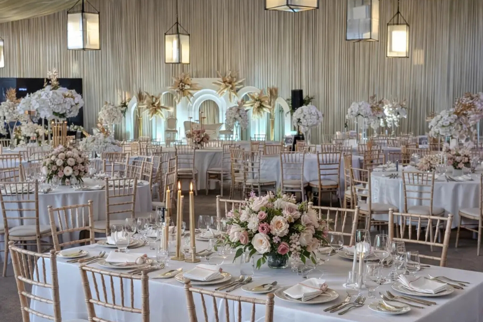 Wedding reception set up at Briar House Barns in East Sussex featuring circle tables with pink and cream floral centrepieces.