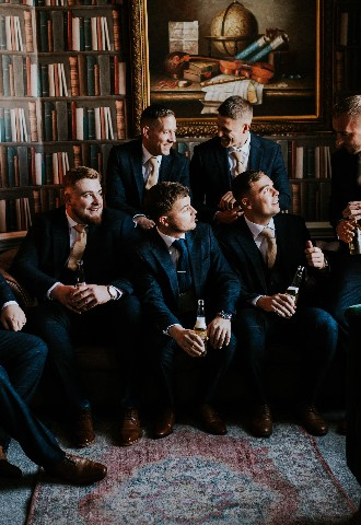 Groom and groomsmen getting ready in library at Hedsor House wedding venue Buckinghamshire