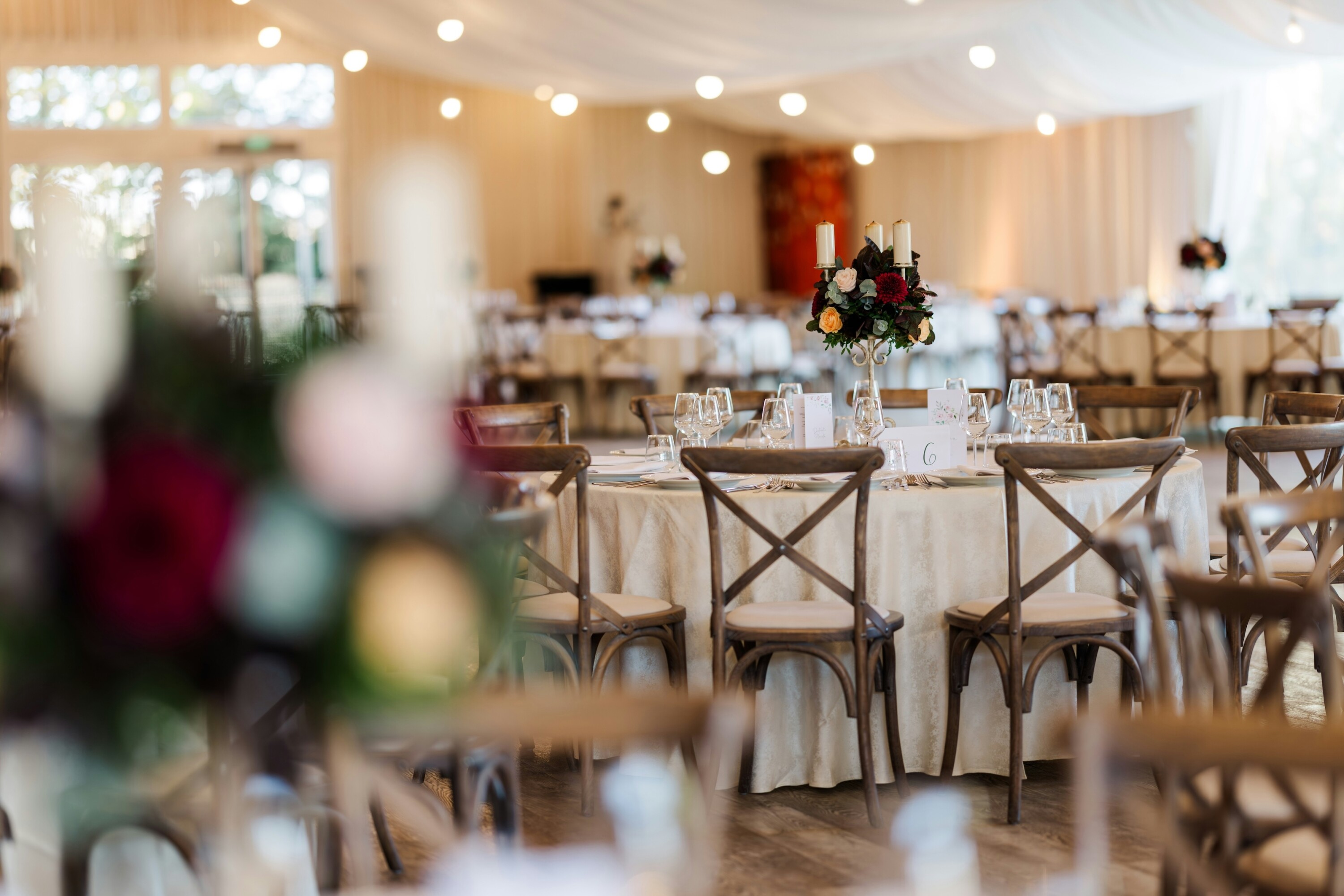 Wedding venue set for a reception with round tables and crossback chairs