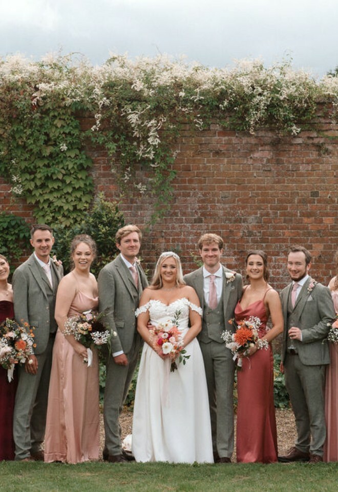 Bridesmaids and groomsmen stand with bride and groom in the walled garden at Elmhay Park
