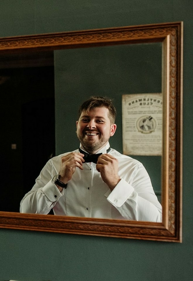 Willian setting his bow tie in front of the mirror