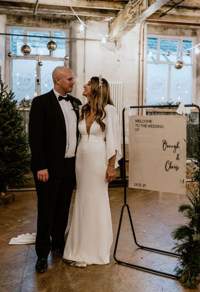 Bride and groom stood by their wedding welcome sign