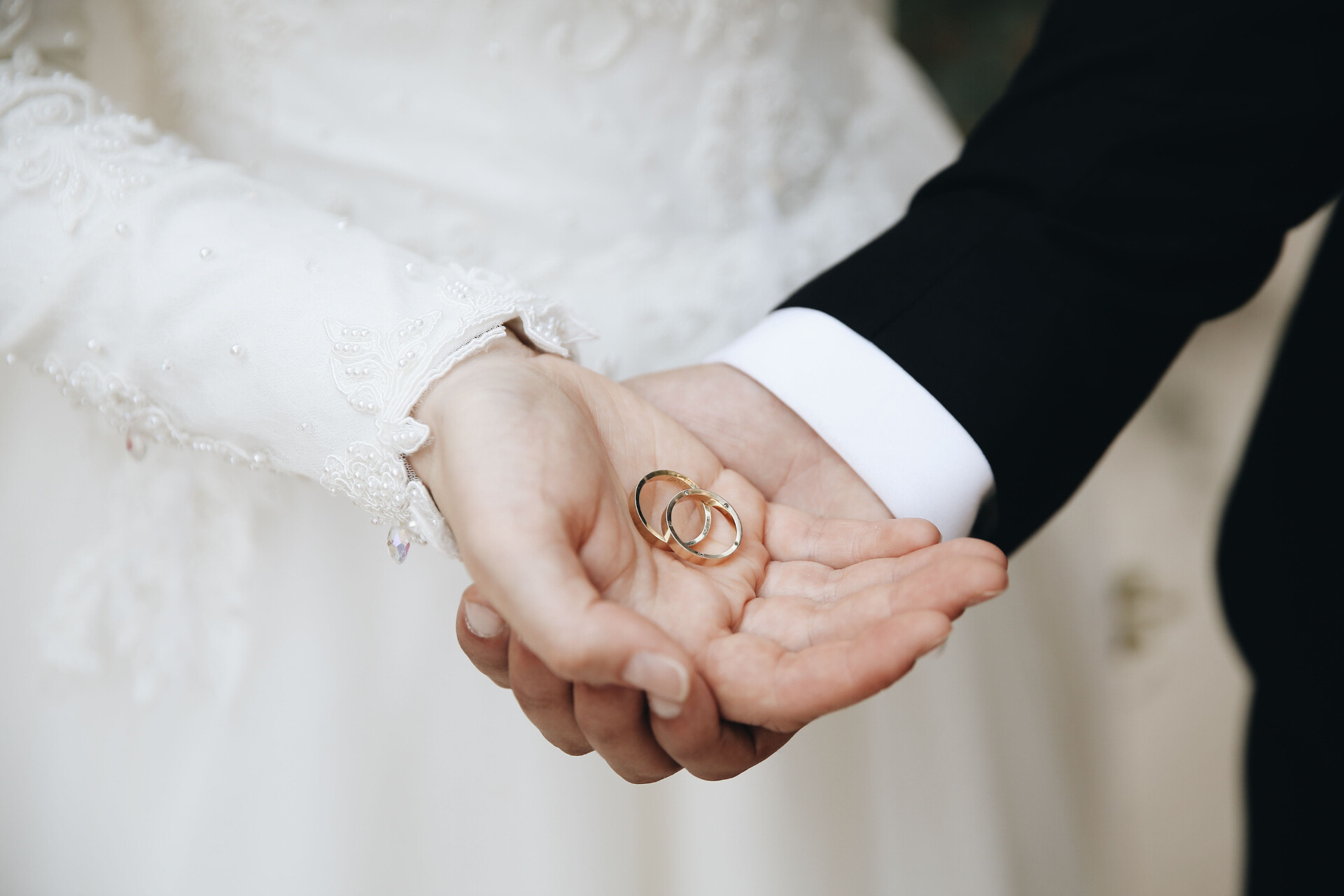 Close-up of wedding rings resting in the hands of a bride and groom