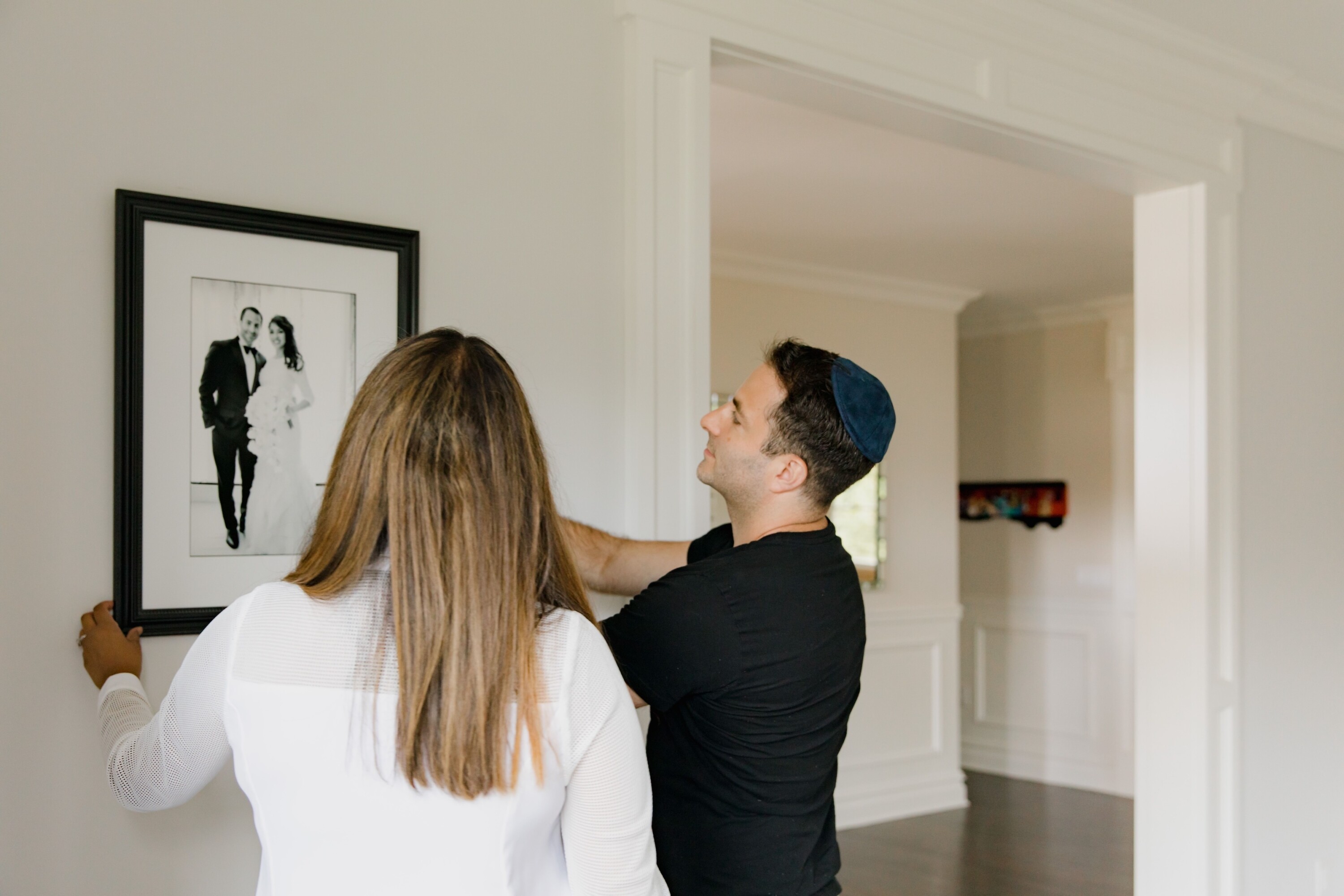 Newlyweds hanging wedding photos on the wall