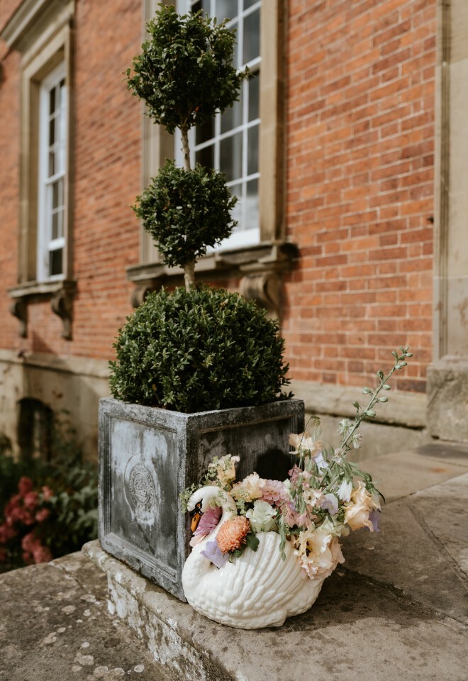 Outdoor wedding decor of a ceramic swan filled with flowers
