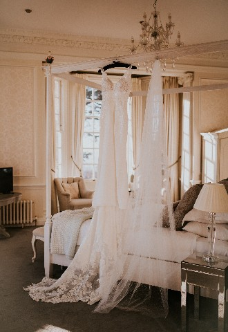Wedding dress hanging on four poster bed at Hedsor House wedding venue Buckinghamshire
