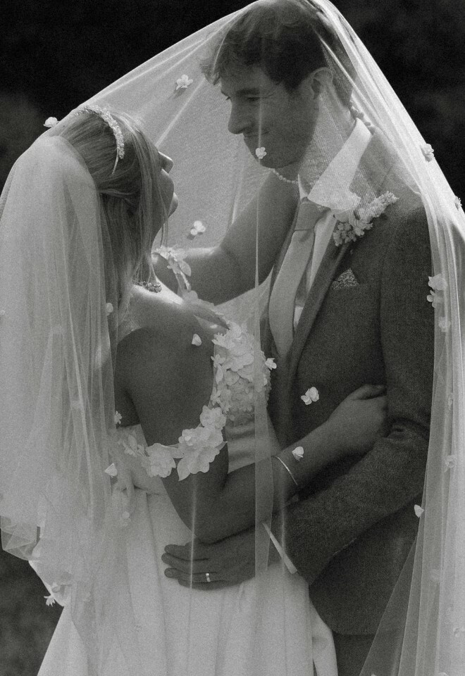 Black and white photo of bride and groom beneath veil
